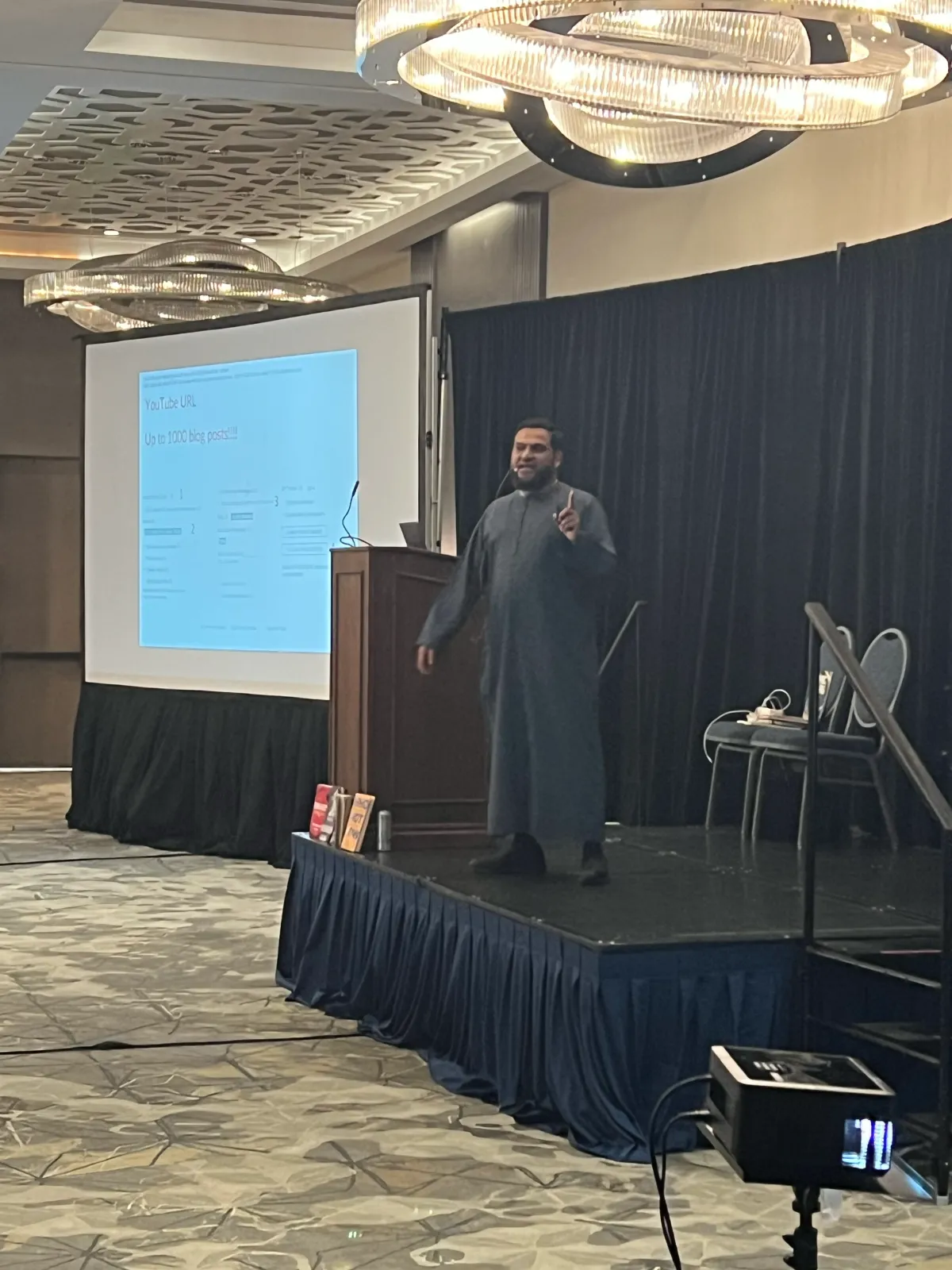 Muhammad Asmal addressing an audience from the stage in Miami