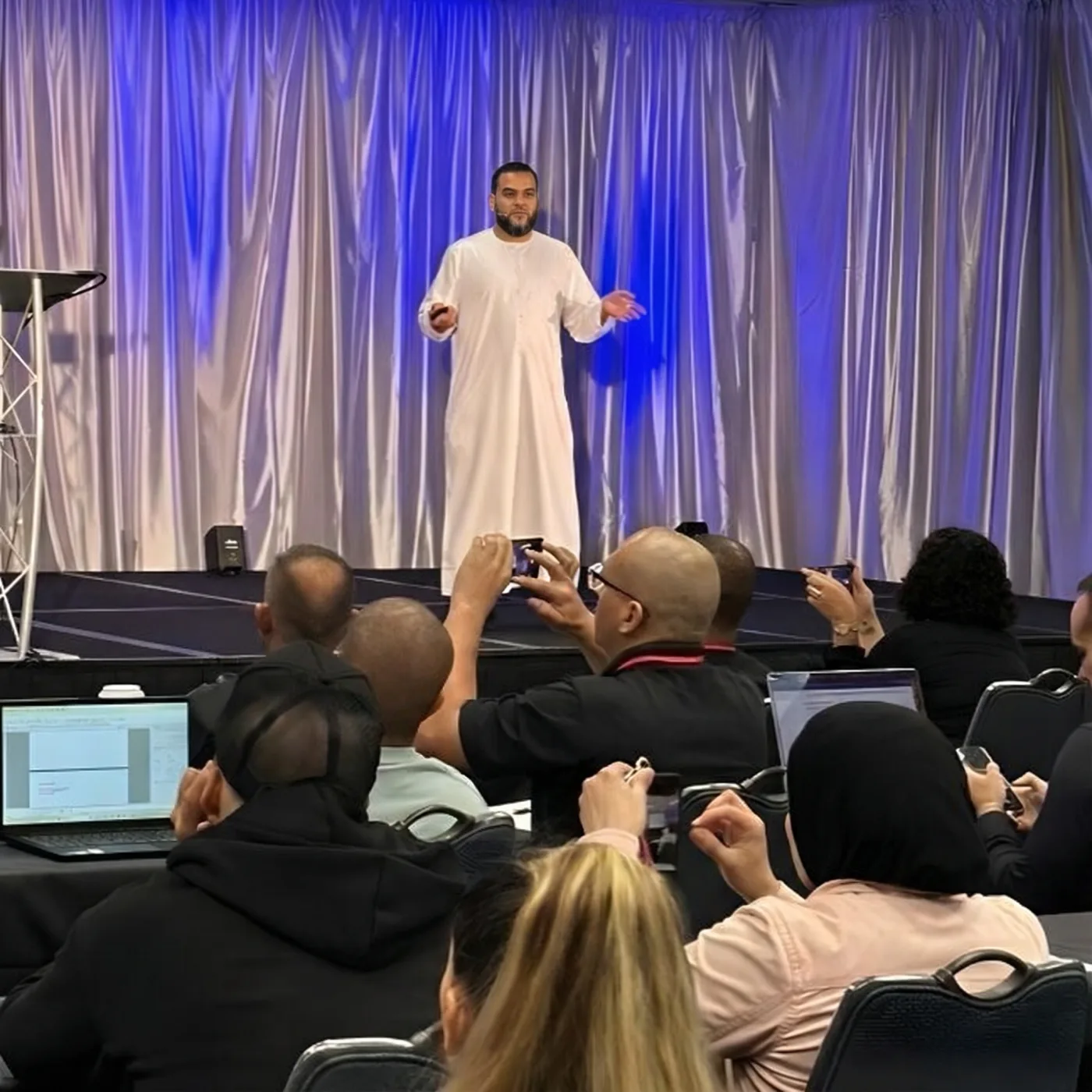 Muhammad Asmal presenting on stage to an audience in Miami